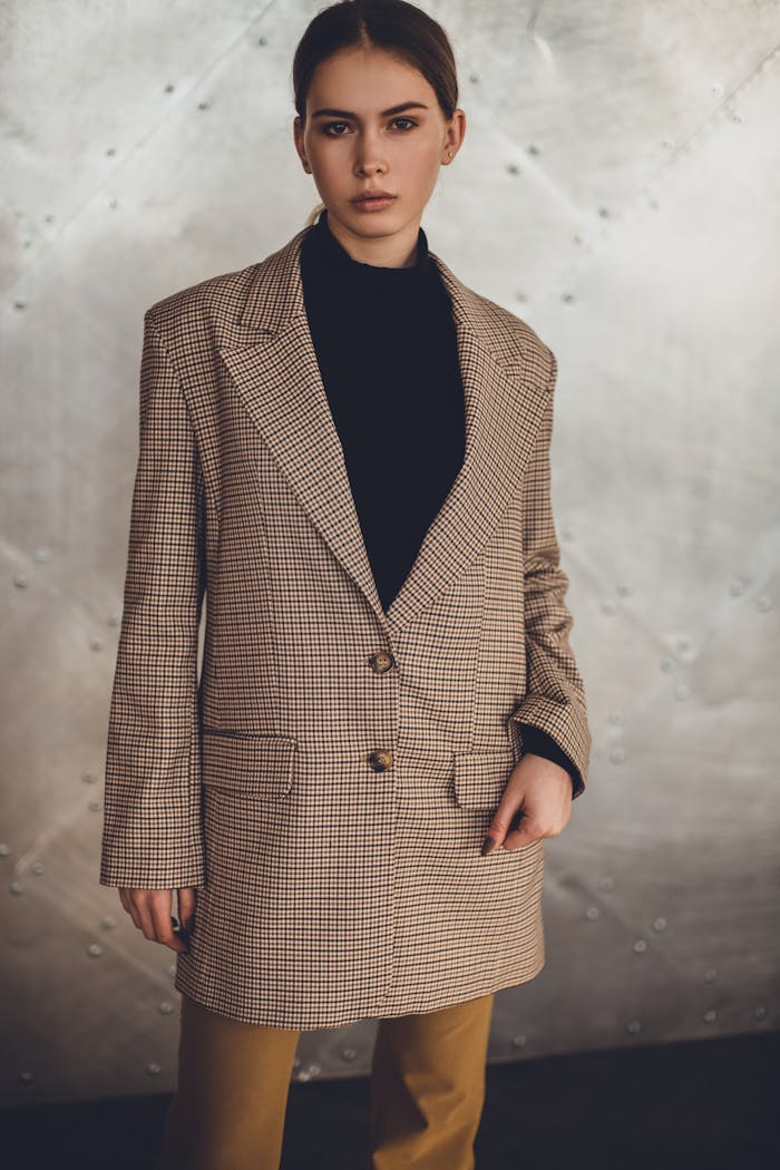 Mastering the First Impression: Your intriguing post title goes here Fashionable woman in a blazer posing confidently against a neutral background. Indoor photo.